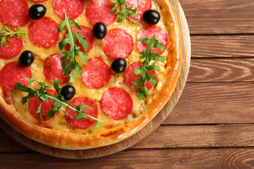 Tasty pizza with salami and olives on wooden background