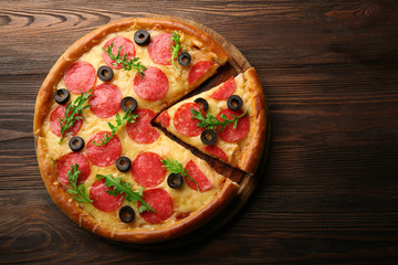 Hot tasty pizza with salami and olives on wooden background