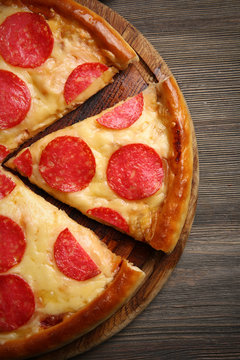 Hot tasty pizza with salami on wooden background