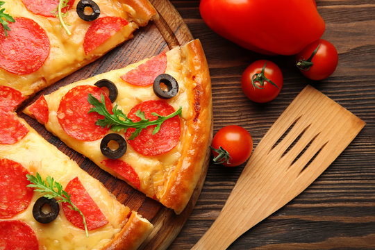 Hot tasty pizza with salami and olives on wooden background, close up