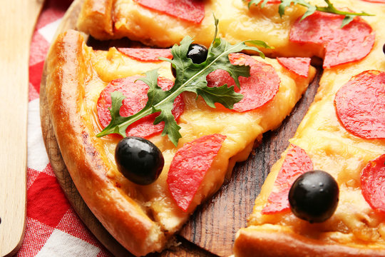 Delicious tasty pizza with salami and olives on wooden background, close up