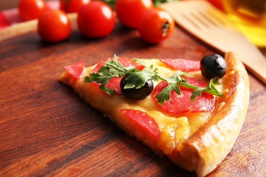 Delicious tasty piece of pizza with vegetables on wooden background, close up