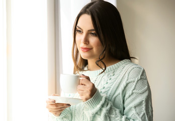 Woman standing near window in the room, close up