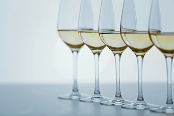 Wineglasses with white wine on wooden table on bright background