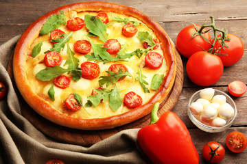 Pizza Margherita with arugula and vegetables on wooden table
