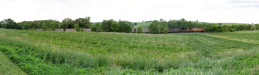 Rural train along fields and woods
