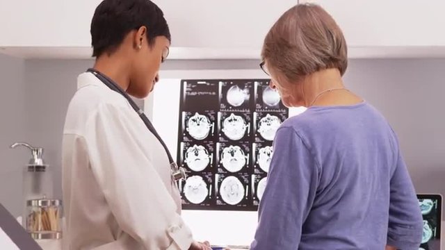 African female doctor reviewing x-ray scans with a senior patient