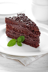 Chocolate cake with chocolate cream on plate, on light background