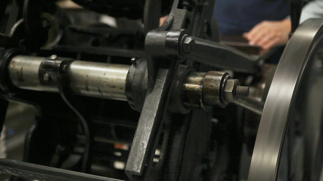 A man operates an antique letterpress machine.