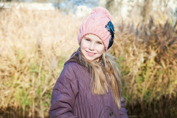 Portrait of the blond young girl at autumn time reed background