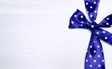 Blue bow in peas on a wooden background.