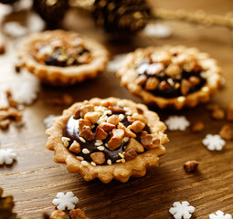 Chocolate cashew nut small tarts on wooden table. A delicious Christmas dessert