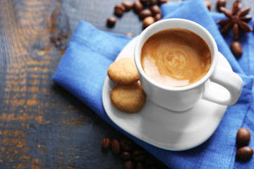 Cup of coffee with spices on wooden table background
