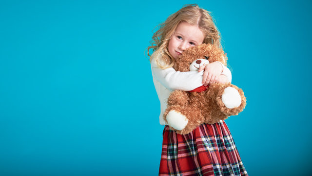 Fabulous little girl hugging brown teddy bear.