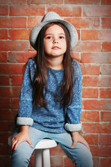 Portrait of little fashion kid girl on bricks wall background