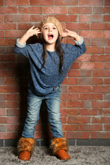 Portrait of little fashion kid girl on bricks wall background