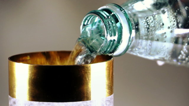 Pouring a glass of mineral water
Sparkling mineral water from the bottle is poured into a glass with a gold rim. Close-up
