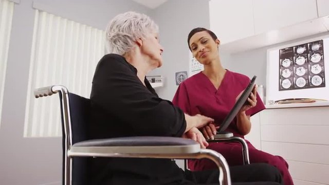Young nurse talking to handicapped patient in a wheelchair