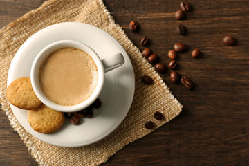 Cup of coffee on sackcloth napkin, on wooden table background