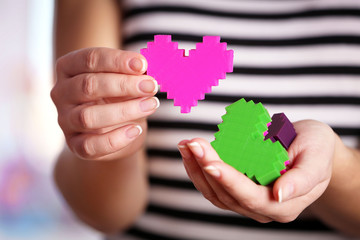 Closeup of plastic puzzle hearts in female hands