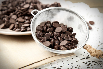 Chocolate morsels on plate, on wooden board
