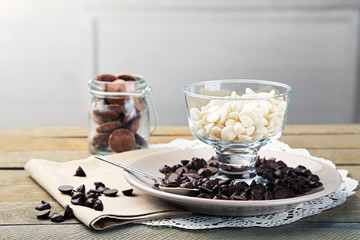 Chocolate morsels in glass jars on wooden background