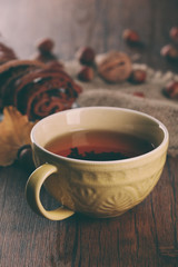 Cup of tea with autumn decor on wooden table.