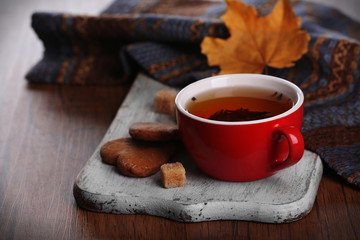 Cup of tea with autumn decor on wooden table.