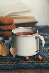 Cup of tea with autumn decor on wooden table.