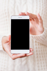 Woman in knitted sweater holding smartphone. Blank display of cellular. Mock up.