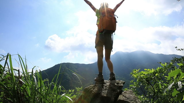 cheering hiking woman on mountain peak