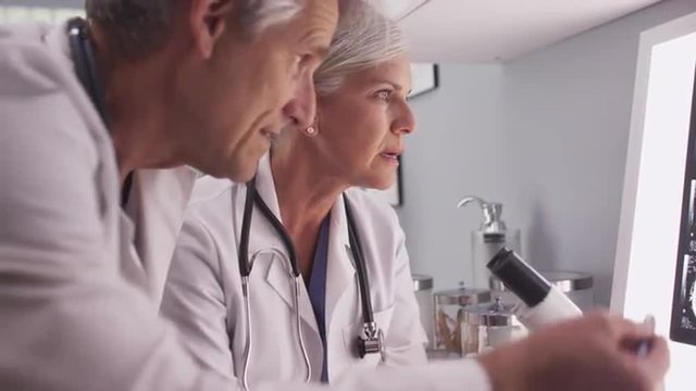 Two mature white neurologists studying x-rays