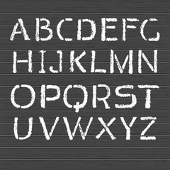 Hand drawn stencil-plate alphabet. White letters on a black board