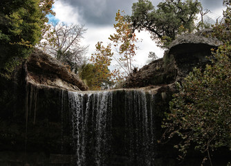 Fototapeta premium Rocky waterfall and trees at Hamilton Pool park in Austin, Texas.