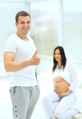 Fototapeta premium man shows that all is well on the background of his pregnant wife sitting