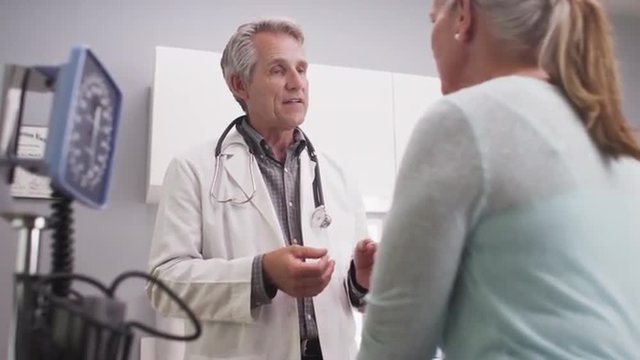 Mid-aged doctor talking to female patient