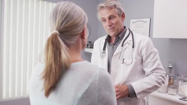 Middle-aged male doctor discussing with senior female patient