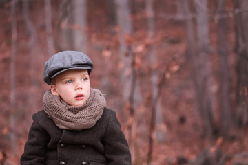 a toddler boy dressed warm looking ahead and thinking