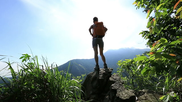 cheering woman hiker open arms at mountain peak cliff