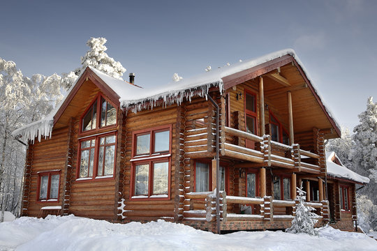 Log home winter with large windows, balcony and porch, daytime.