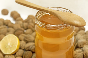 Jar of honey and spoon with lemon and walnuts