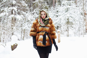 Fototapeta premium winter forest.beautiful young Woman in Fur Coat,leather gloves and scarf