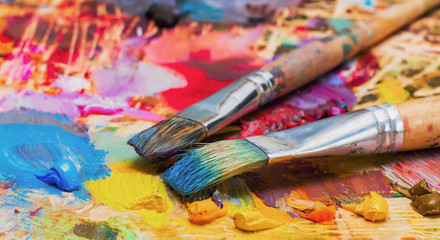 Fototapeta premium Used brushes on an artist's palette of colorful oil paint
