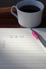 To do list  with a pen and cup of fresh coffee on wood background in morning 