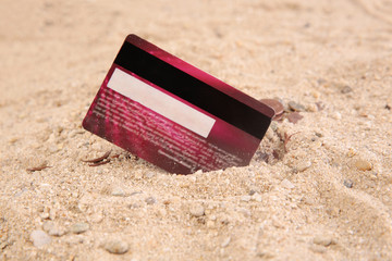 credit card in the sand with coins