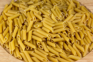 Uncooked Penne Pasta on Wooden Tray