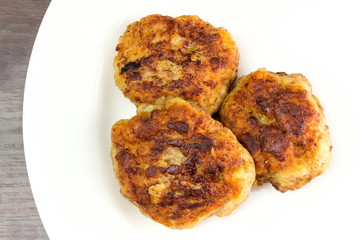 Fried meat cutlets on white plate, top view