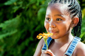 Little african girl blowing at flower.