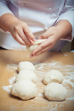 Woman's hands knead dough. Selective focus. Toned