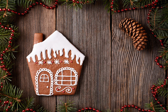 Gingerbread House Cookie Christmas Composition In New Year Decorations Frame On Vintage Wooden Table Background. Homemade Traditional Dessert Icing Recipe. Top View.